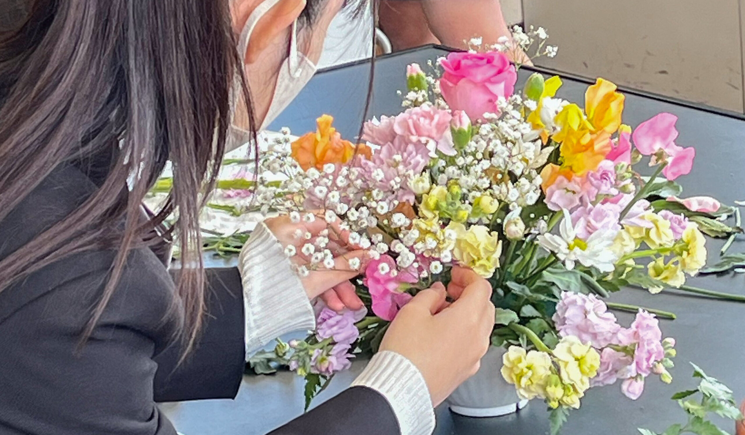 花を手にアレンジをする女生徒の写真